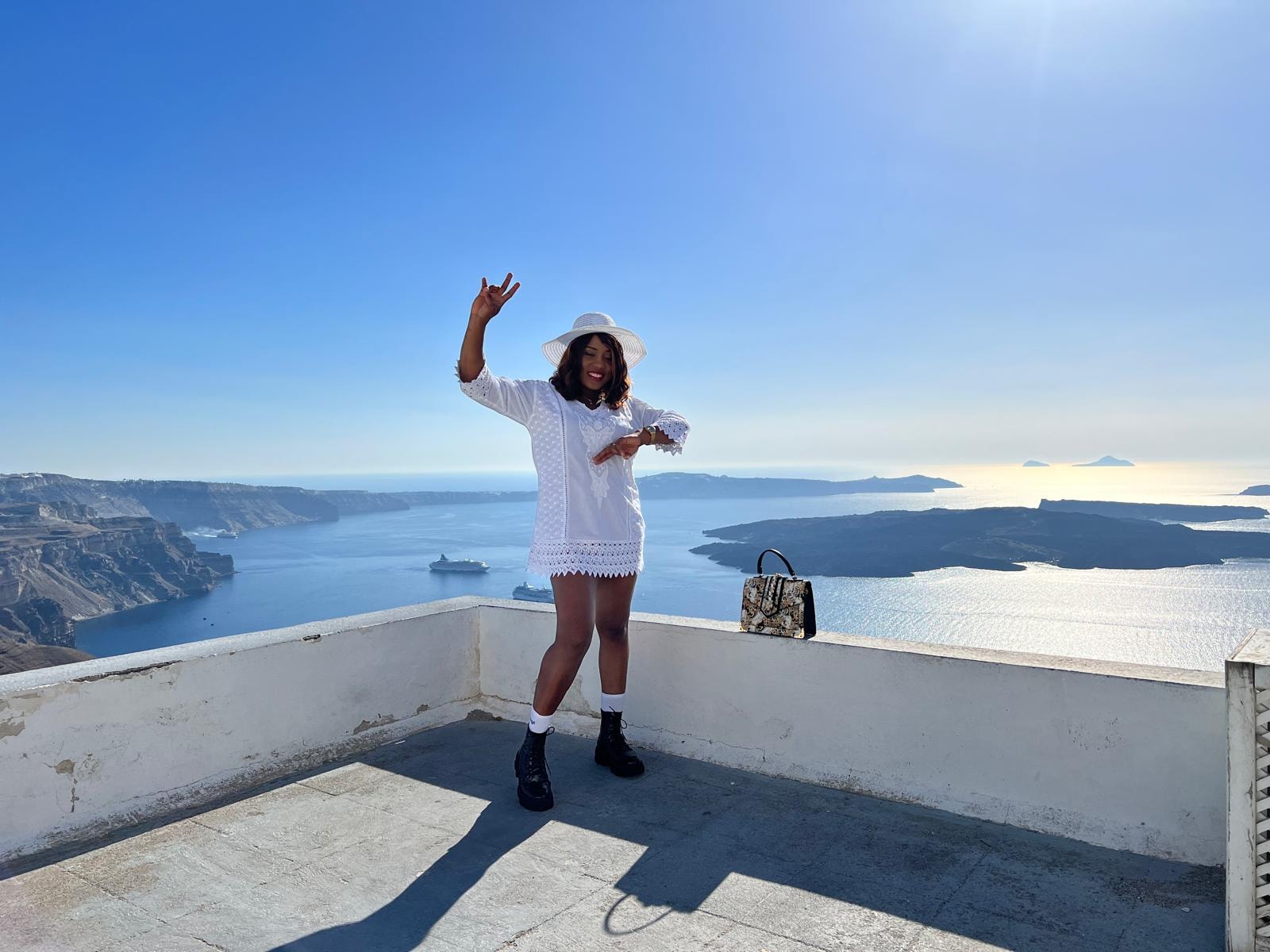 Traveller celebrating on a terrace overlooking the Santorini caldera